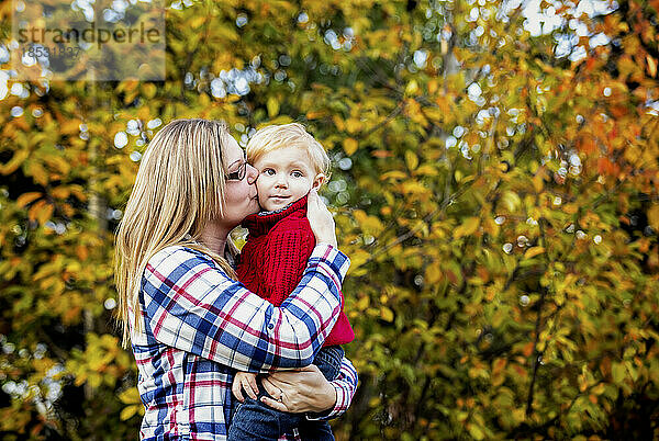 Mutter hält und küsst ihren kleinen Sohn im Freien im Herbst; Edmonton  Alberta  Kanada