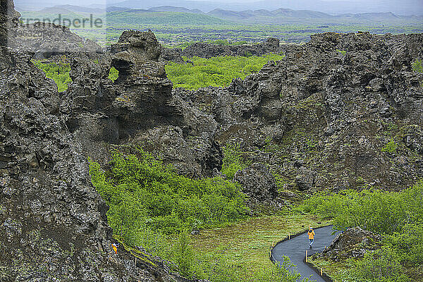 Wanderer geht an den Dimmuborgir-Lavaformationen in Island vorbei; Island