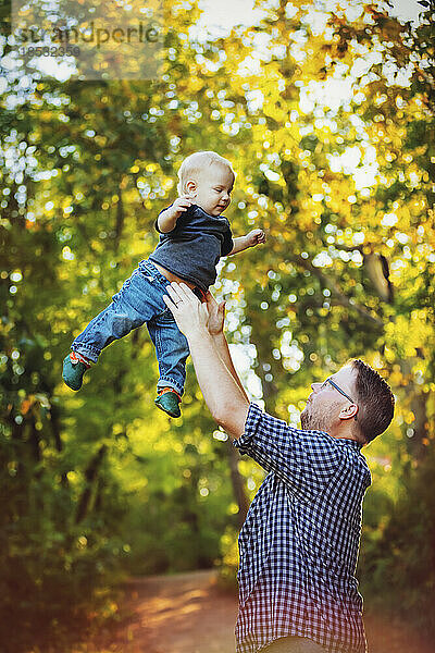 Vater spielt mit seinem kleinen Jungen in einem Park und wirft ihn in die Luft; Edmonton  Alberta  Kanada