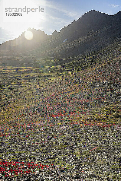 Sonnenstrahlen über der farbenfrohen Herbsttundra entlang des Wanderwegs durch die Chugach Mountains im Chugach State Park; Anchorage  Alaska  Vereinigte Staaten von Amerika