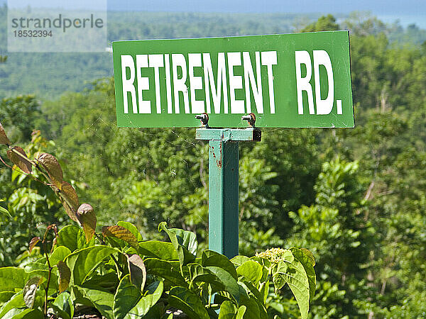 Straßenschild in der üppigen Landschaft mit der Aufschrift Retirement Road (Straße für Rentner); Bluefields Bay  Jamaika