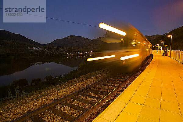 Zug verlässt einen Bahnhof in der Abenddämmerung; Douro-Tal  Portugal