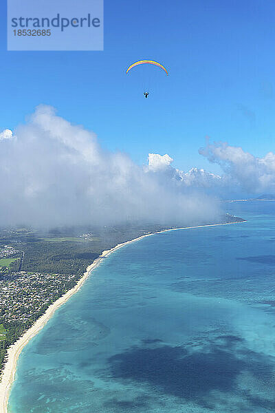 Gleitschirmflieger  der hoch über der Küste von Honolulu mit dem türkisfarbenen Wasser des Pazifischen Ozeans und einem blauen Himmel fliegt; Oahu  Hawaii  Vereinigte Staaten von Amerika