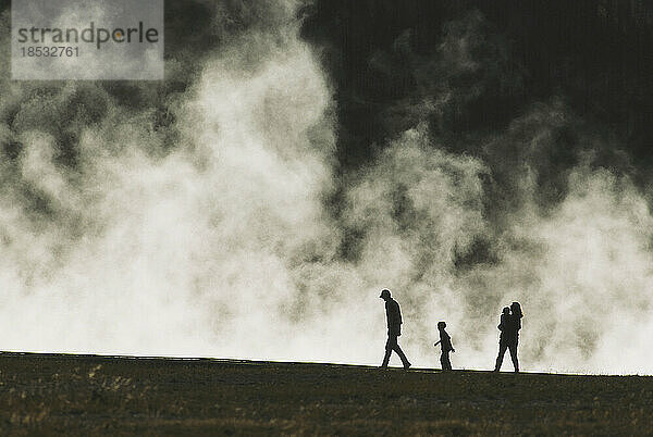 Silhouettierte Familie spaziert an einer dampfenden heißen Quelle im Yellowstone-Nationalpark  USA; Wyoming  Vereinigte Staaten von Amerika