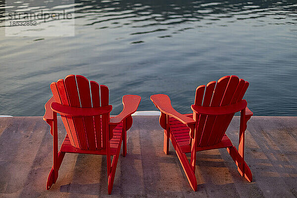 Zwei rote Adirondack-Stühle auf einem Steg am Sproat Lake bei Sonnenuntergang  Vancouver Island  BC  Kanada; Vancouver Island  British Columbia  Kanada