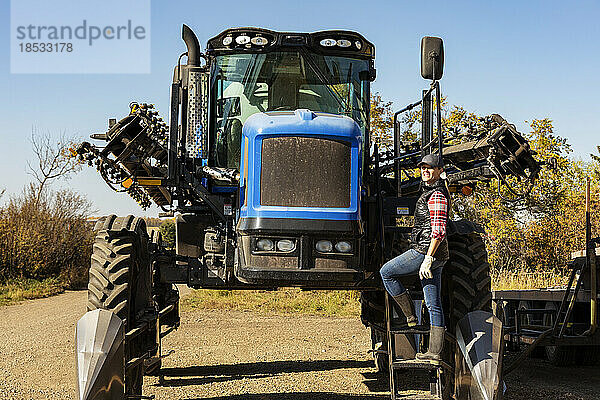 Porträt einer Landwirtin  die auf den Stufen eines Traktors mit Sämaschinenanbau steht; Alcomdale  Alberta  Kanada