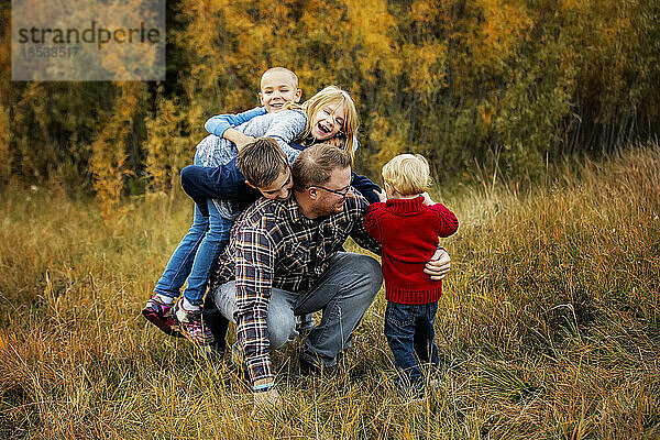 Ein Vater tobt mit seinen vier Kindern in einem Stadtpark im Herbst; Edmonton  Alberta  Kanada