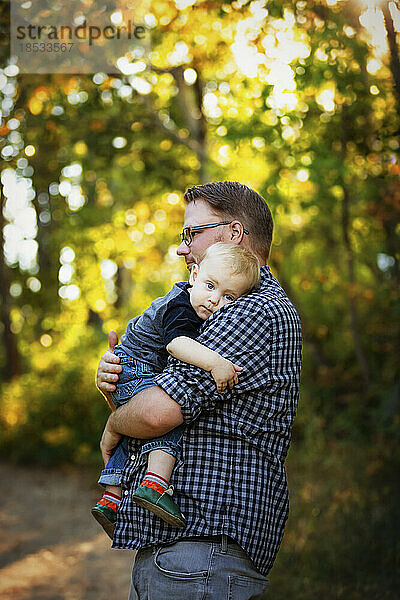 Vater hält und tröstet seinen kleinen Jungen im Freien in einem Park im Herbst; Edmonton  Alberta  Kanada
