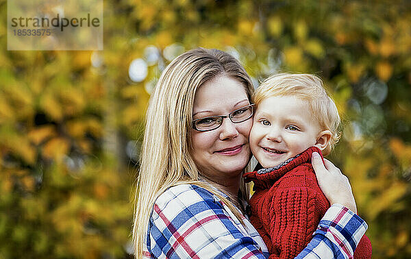 Porträt einer Mutter im Freien  die ihren kleinen Sohn im Arm hält  in einer Parkanlage im Herbst; Edmonton  Alberta  Kanada