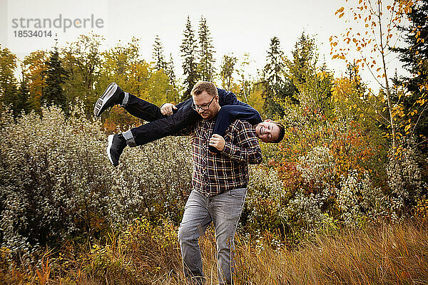 Vater tobt mit seinem Sohn im Freien in einem Park im Herbst; Edmonton  Alberta  Kanada
