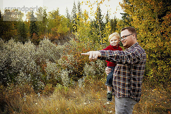 Porträt eines Vaters mit seinem kleinen Sohn  der im Herbst die Natur in einem Park erkundet; Edmonton  Alberta  Kanada