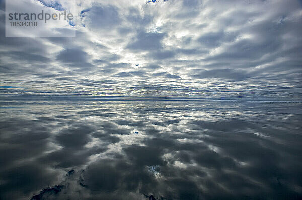 Spiegelbild eines wolkenverhangenen Himmels  der sich auf der Wasseroberfläche des Ozeans spiegelt; Svalbard Archipelago  Norwegen