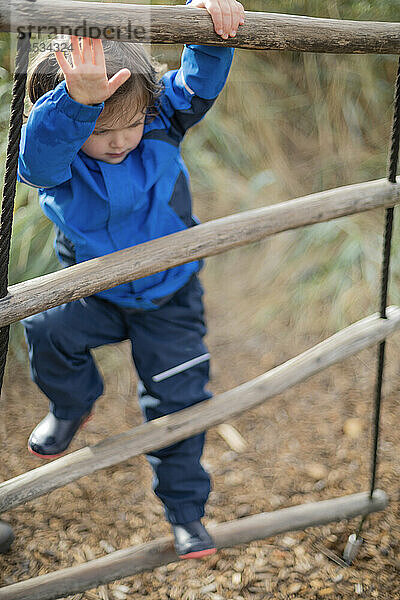 Mädchen im Vorschulalter klettert auf eine Leiter  während sie auf einem Spielplatz spielt; West Vancouver  British Columbia  Kanada