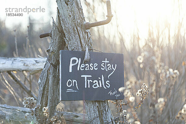 An einem verwitterten Pfosten hängendes Schild  das Wanderer auffordert  auf dem Weg zu bleiben; Ottawa Valley  Ontario  Kanada