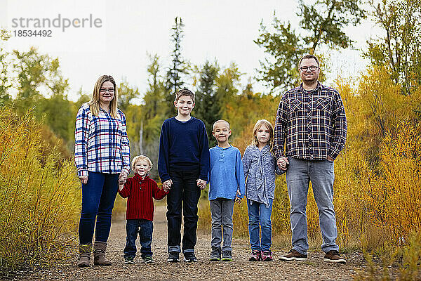 Sechsköpfige Familie steht Hand in Hand in einem Park im Herbst; Edmonton  Alberta  Kanada