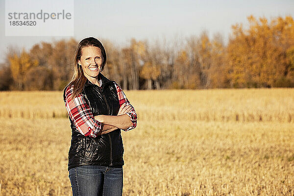 Ein Porträt einer attraktiven Bäuerin  die zur Erntezeit auf einem Feld für die Kamera posiert; Alcomdale  Alberta  Kanada