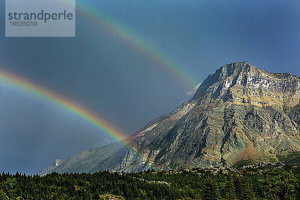 Doppelter Regenbogen mit Berg und dunkelblauem Himmel im Waterton Lakes National Park; Waterton  Alberta  Kanada