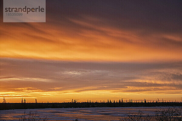 Sonnenaufgang über dem borealen Wald und dem zugefrorenen See entlang des Ufers der Hudson Bay  Manitoba  Kanada; Churchill  Manitoba  Kanada