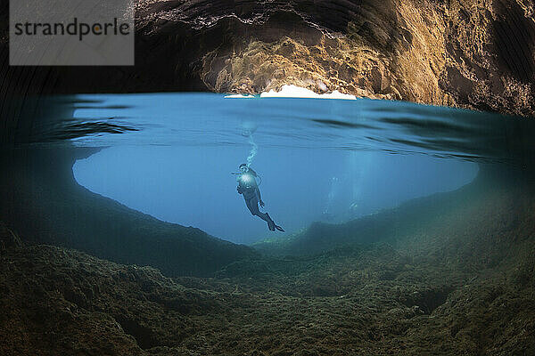 Halb oben  halb unten Aufnahme eines Tauchers am Eingang zu einer Höhle  die die Oberfläche auf der Insel Gato  Bohol Sea  Philippinen  Südostasien  durchbricht; Gato  Philippinen