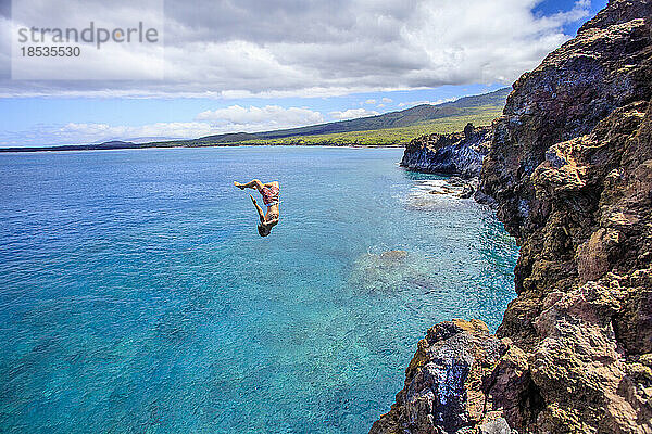 Klippenspringer  der kopfüber in der Luft von einer Klippe an der Südseite der La Perouse Bay springt  Maui  Hawaii  USA; Maui  Hawaii  Vereinigte Staaten von Amerika