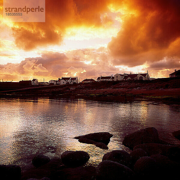 Dramatische Wolken bei Sonnenuntergang über einer Küstenstadt in Irland; Irland