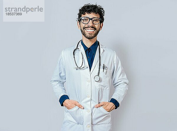 Lächelnder Arzt auf isoliertem Hintergrund. Glücklicher Arzt mit Händen in den Taschen. Porträt eines lächelnden jungen Arztes isoliert
