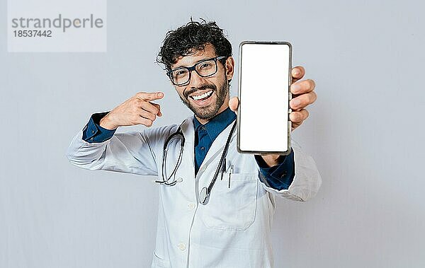 Glücklicher Arzt zeigt Handybildschirm in die Kamera. Lächelnder Arzt zeigt Handybildschirm mit dem Finger isoliert