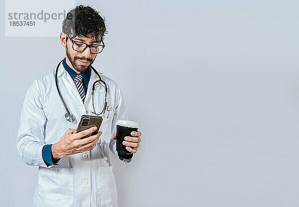 Junger Arzt mit Kaffee zum Mitnehmen und Telefon. Arzt mit Telefon und Coffee to go in der Hand