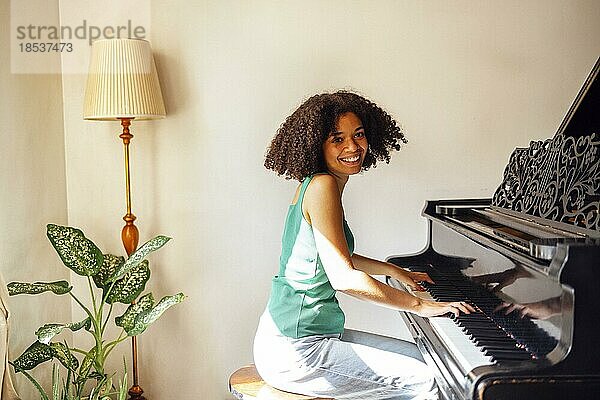 Junge schwarze Frau spielt Klavier. Glücklich lächelnde Frau genießen Spaß lernen  Klavier Musikinstrument zu spielen