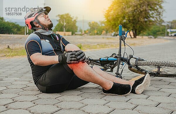 Männlicher Radfahrer sitzt mit Knieschmerzen auf dem Bürgersteig. Konzept eines Radfahrers mit Knieverletzung im Freien  Radfahrer mit Knieschmerzen im Freien