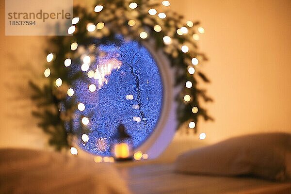 Weihnachtsdekoration zu Hause. Atmosphärische Indoor Foto mit alten Vintage leuchtenden Laterne durch runde Fenster mit Baumzweig und Weihnachtsbeleuchtung dekoriert. Einstellung Urlaub Stimmung während der Winterferien im Haus