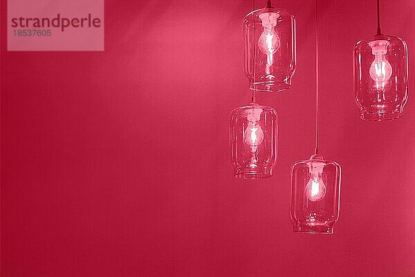 Low Winkel Set von kreativen transparenten Glaslampen mit leuchtenden Glühbirnen hängen an der Decke im Raum mit viva magenta Hintergrund