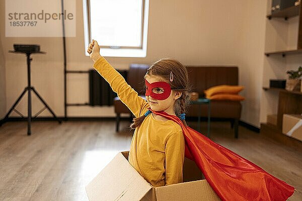 Superhelden Kind. Superheldenkind  das zu Hause in einer Kiste spielt. Bewegung  Erfolg und freudiges Spielkonzept