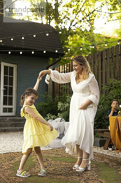 Mutter und kleine Tochter haben Spaß im Freien. Hochzeit  schöne Braut mit einem kleinen Mädchen tanzen zusammen. Liebe  Familie  Feier
