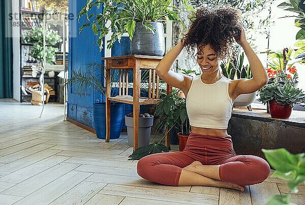 Junge Erwachsene glücklich fit schlank gesund afroamerikanischen ethnischen Frau trägt Sportkleidung in Yogapose zu Hause im Wohnzimmer sitzen  tun Fitness Morgen Workout Übungen Ausbildung