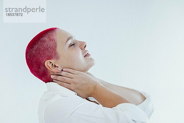 Schöne entspannte Frau in heller Kleidung und roten Haaren mit Kopfschmerzen beim Ausruhen an einem sonnigen Wochenendtag zu Hause. Körper positives Konzept