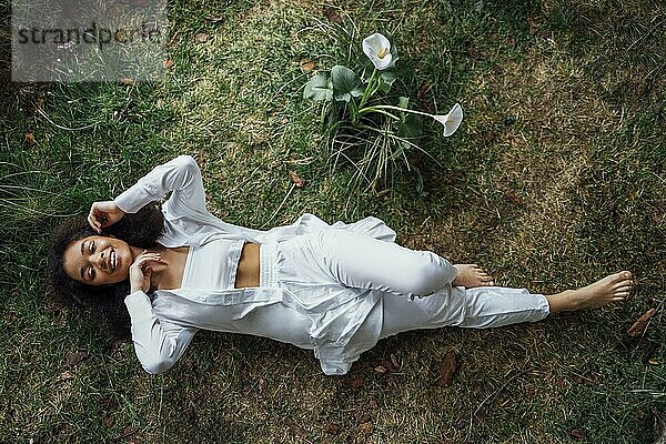 Mode und Schönheit schießen eine charmante Mixed race Mädchen in weiß Schönes Mädchen auf dem Gras in ihrem gelben Kleid in ungewöhnlichen Studio. Junge Frau genießt die Natur