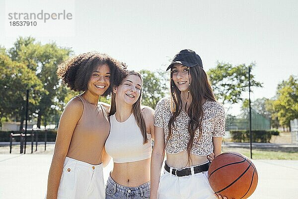 Multikulturelle Gruppe von jungen weiblichen Freunden  die sich im Freien treffen und Spaß haben. Stilvolle coole Teenagermädchen versammeln sich auf dem Basketballplatz  Freunde bereit für das Spielen von Basketball im Freien