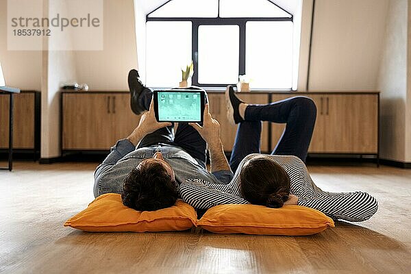 Mann und Frau beim Chatten in einem sozialen Netzwerk. Frau schaut Video auf digitalem Tablet. Ehepaar verbringt Zeit miteinander