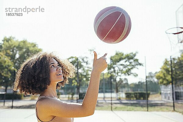 Mixed race junge lächelnde Frau im Freien und Spaß haben. Stilvolle kühlen Teenagermädchen Versammlung am Basketballplatz  Basketball spielen im Freien