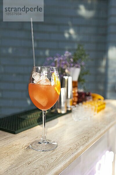 Aperol Spritz Cocktail im Glas mit frischer Orange und Eis auf blauem Hintergrund. Details einer Sommerparty im Freien