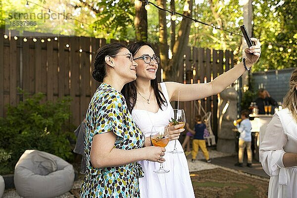Glückliche Freundinnen verbringen Zeit miteinander  junge Frau trinkt Aperol Spritz Cocktail auf im Freien Hochzeitsparty  machen selfi zusammen. Glück  Freundschaft und Feier concpt
