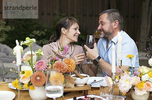 Glückliches Paar im Gespräch und Flirten in der Terrasse Garten halten Gläser mit Wein. Menschen Toasting zusammen im Freien Hochzeit Sommerparty