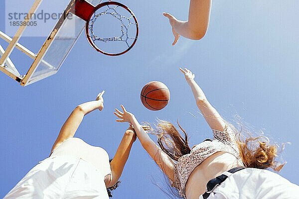 Multikulturelle Gruppe von jungen Freundinnen  die sich im Freien treffen und Spaß haben. Stilvolle coole Teenagermädchen versammeln sich am Basketballplatz  Freunde spielen Basketball im Freien