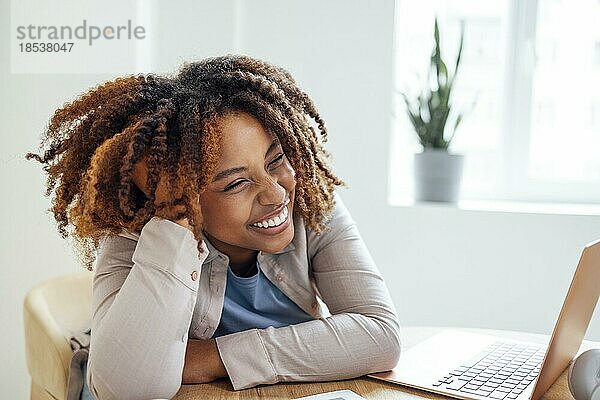 Junge afroamerikanische Frau arbeitet an einem Laptop. Fokussierte Studentin schaut auf Computerbildschirm und beobachten Webinar oder tun Videochat per Webcam. Fernunterricht oder Home Office Konzept