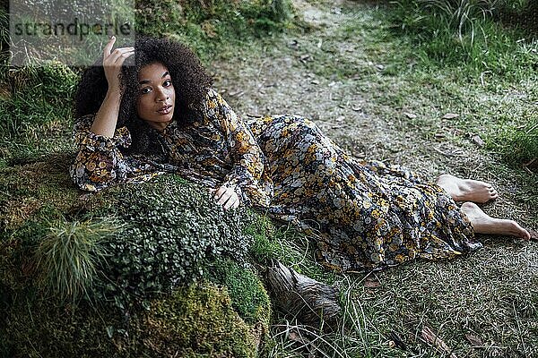 Mode und Schönheit Schießen eine charmante Mixed Rasse Mädchen in einem langen Kleid. Schönes Mädchen auf dem Gras in ihrem gelben Kleid in ungewöhnlichen Studio. Junge Frau genießt die Natur