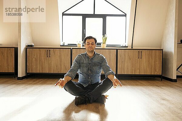 Handsome hispanischen Mann trägt Jeans lässigen Hemd sitzen auf dem Boden zu Hause entspannen  tun Meditation Geste mit den Fingern. Yogakonzept