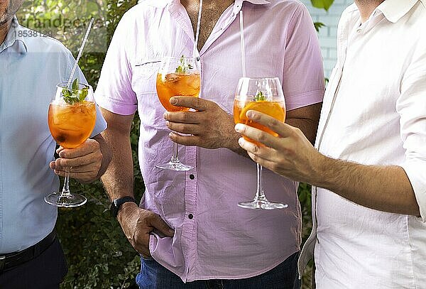 Männliche Freunde verbringen Zeit miteinander und trinken einen Aperol Spritz Cocktail auf einer Sommerparty. Zusammen reden