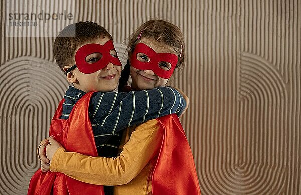 Porträt eines Teams von zwei jungen Superhelden  Bruder und Schwester  auf beigem Hintergrund. Superhelden Kind. Superheld Kind spielt zu Hause. Idee  Freiheit  Freundschaft  glückliches Kindheitskonzept