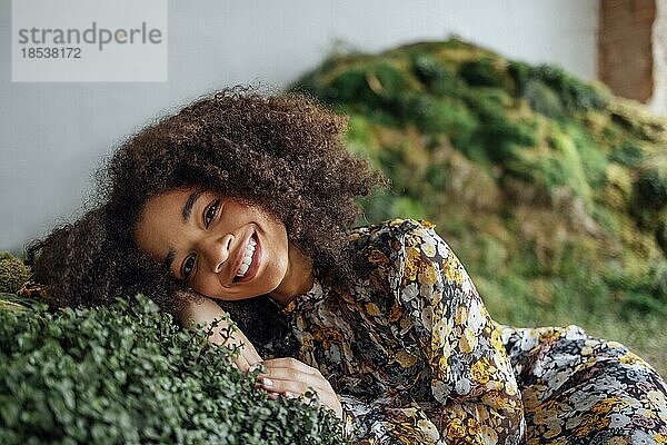 Mode und Schönheit Schießen eine charmante Mixed Rasse Mädchen in einem langen Kleid. Schönes Mädchen auf dem Gras in ihrem gelben Kleid in ungewöhnlichen Studio. Junge Frau genießt die Natur